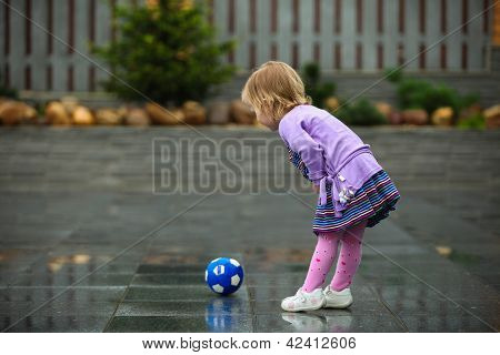 bambina gioca con una palla sulla strada