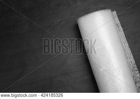 Bubble Wrap Roll On Black Background, Top View. Space For Text