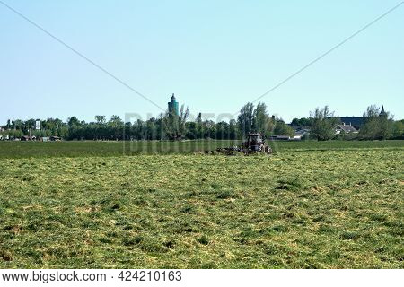 Leerdam, The Netherlands June1, 2021:grassland With Tractor Mower And Rake, Grass Ready To Be Ensile