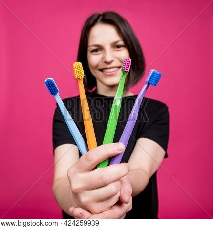 Beautiful Happy Young Woman With Different Colored Toothbrushes On Blank Pink Background