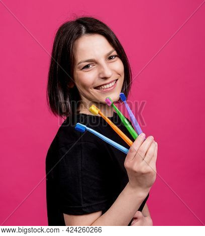 Beautiful Happy Young Woman With Different Colored Toothbrushes On Blank Pink Background