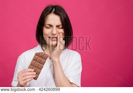 Beautiful Young Woman Bites A Bar Of Chocolate And Has A Toothache