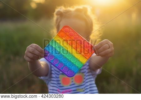 The Child Plays With A Colorful Rainbow Game Of Poppit. Silicone Fidget Close-up.