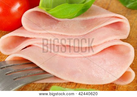 doblado en lonchas de jamón sobre una tabla de cortar de madera con un tenedor