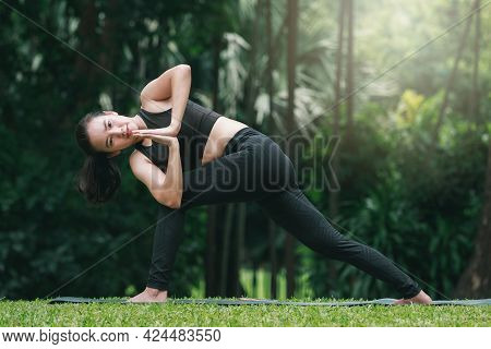 Asian Woman Practicing Yoga In Prep Poses For Side Crane Pose For Parsva Bakasana On The Mat In Outd