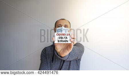 Covid-19 Delta Strain Symbol. White Card With Words 'covid-19 Delta Strain'. A Young Man In A Grey W