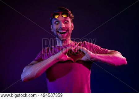 Portrait Of Attractive Amazed Cheerful Guy Showing Heart Shape Having Fun Isolated Over Dark Neon Pu