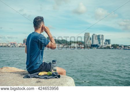 The Young Athlete Was Listening To Music And Looked At The City During His Break After Exercise. Mus
