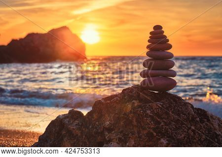 Concept of balance and harmony. Cairn stack of stones pebbles cairn on the beach coast of the sea in the nature on sunset. Meditative art of stone stacking