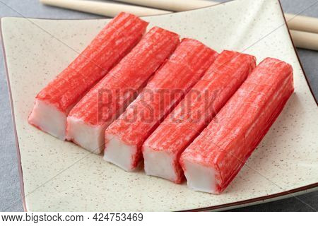 Plate with red Japanese Surimi sticks close up  