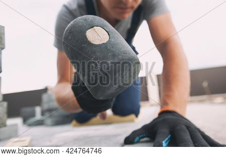 Worker lining paving slabs path