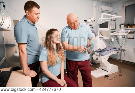 Male Stomatologist Pointing At Dental Scan While Working With Colleagues In Dental Office With Moder