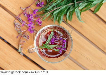 Fireweed Herbal Tea In The Glass Cup On Wooden Table With Fresh Fireweed Flowers On Background. Top 