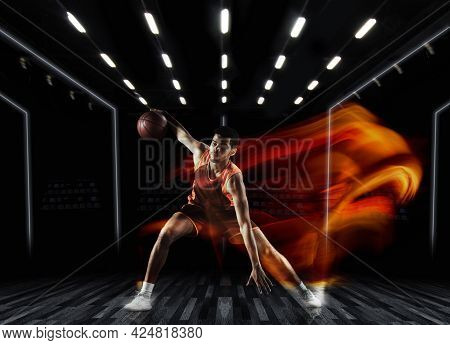 One Young Sportsman Basketball Player Training In Gym, Idoors Isolated On Dark Background In Mixed L