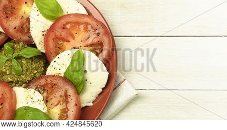 Caprese Salad In A Plate Over Wooden Background. Fresh Tomato And Mozzarella Cheese With Basil Leave