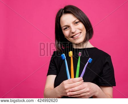 Beautiful Happy Young Woman With Different Colored Toothbrushes On Blank Pink Background