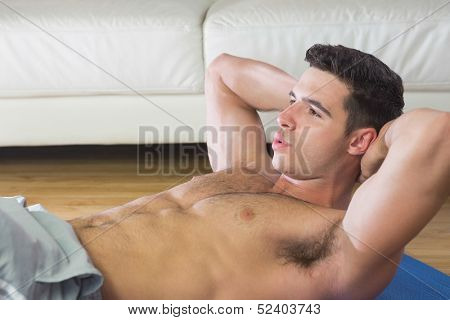 Determined handsome man doing sit ups in bright living room