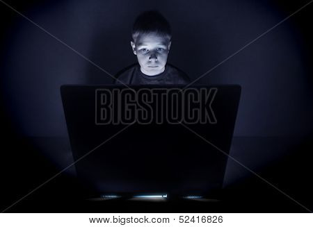 12 year old boy illuminated by the blue light of a computer monitor