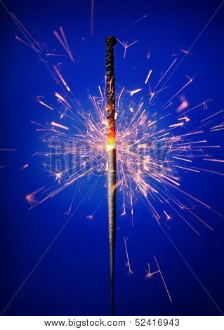 Photo of a sparkler against blue background.