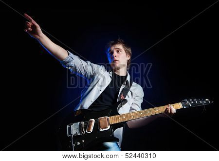 portrait of young man with guitar on dark background