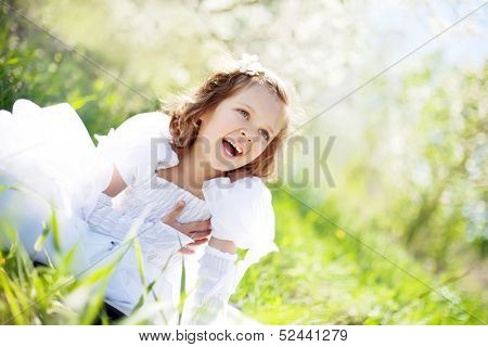 The beautiful little girl, with bush blossoming apple-tree, smil