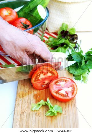 Man skærer modne tomater til sommer grøntsager salat