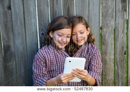 twin girls fancy dressed up pretending be siamese with dad shirt playing with tablet pc