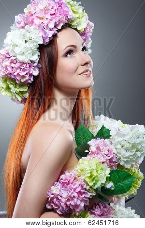 Close-up portrait of beautiful young redheaded girl in a chaplet with  flowers