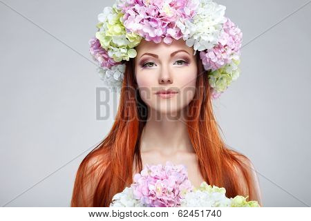Close-up portrait of beautiful young redheaded girl in a chaplet with  flowers