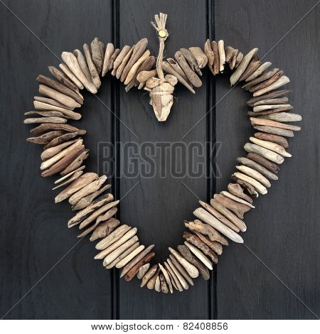 Driftwood heart hanging on a dark oak wood background.
