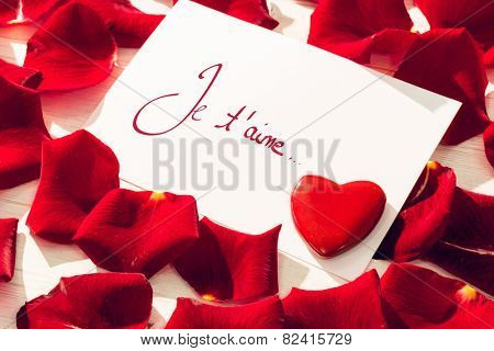 Valentines love hearts against card with red rose petals