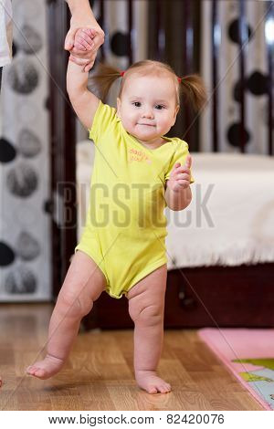 baby taking first steps with mother help