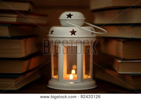 Books and decorative lantern on table and wooden planks background