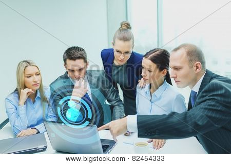 business, technology and people concept - serious business team with laptop computers and user icon projection having discussion in office