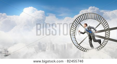 Young businessman running in huge hamster wheel