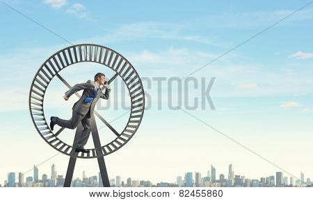 Young businessman running in huge hamster wheel