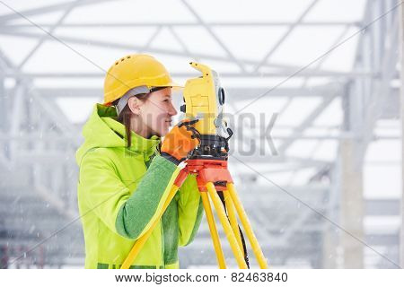 female surveyor worker working with theodolite transit equipment at road construction site outdoors