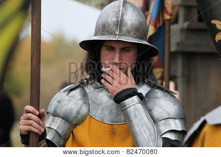 MILOVICE, CZECH REPUBLIC - OCTOBER 23, 2013: Actor dressed as a medieval guard smokes during the filming of the new movie The Knights directed by Carsten Gutschmidt near Milovice, Czech Republic.