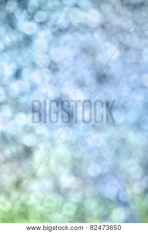 Soft boken background fading from blue of the sky to green green of the grass.