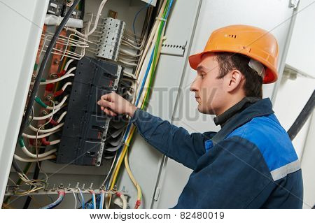 Young adult electrician builder engineer screwing equipment in fuse box