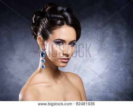 Young, beautiful and rich woman in jewels of platinum and stones over luxury background 