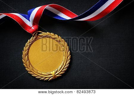 Gold medal on black with blank face for text, concept for winning or success