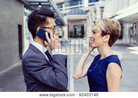 Business people standing in stret with their mobiles