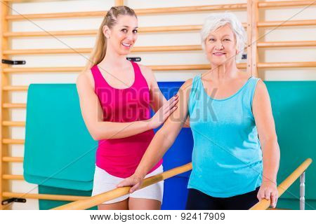 Walking Rehab in with senior woman, trainer guiding her to remobilization