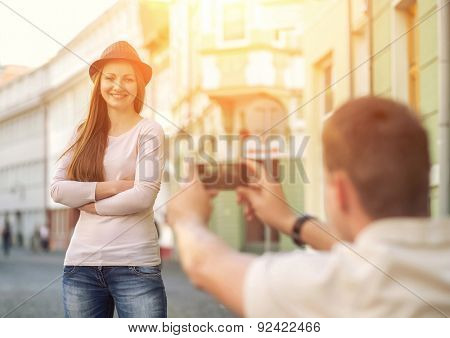 Touristic couple shooting on the modile phone at the city streets under sunlight.