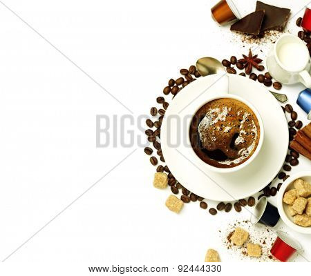 Top view of a cup of coffee with coffee beans, sugar, milk and capsules