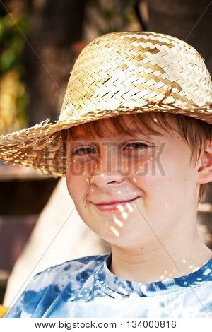 young boy with straw hat is happy and smiles
