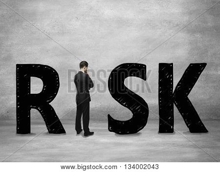 Business risk concept with thoughtful businessman standing instead letter I on concerete background