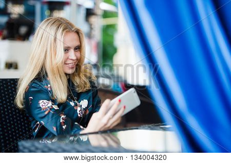 young woman making self portrait using smartphone. girl making selfie. woman in cafe. woman alone. self portrait in cafe outdoors. smile. smilimg. gadget. self portrait. coffe break. coffee time.