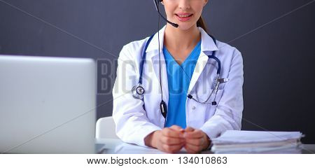 Doctor wearing headset sitting behind a desk with laptop.